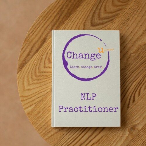 White note book on wooden table - NLP Practitioner Course Manual
